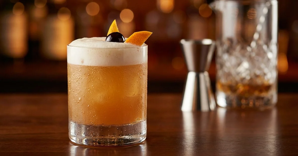 Professional photograph of a Amaretto Sour cocktail with garnish in elegant bar setting