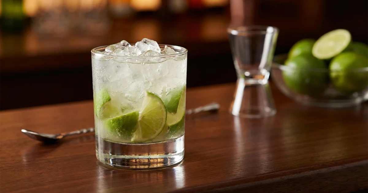 Professional photograph of a Caipirinha cocktail with garnish in elegant bar setting